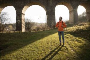 front-view-man-road-trip-nature-posing-aqueduct