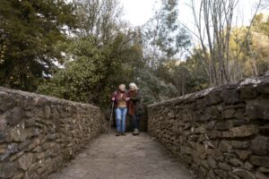 two-senior-women-crossing-stone-bridge-while-out-nature (1)